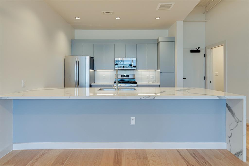 1023 Lipscomb Street, Unit 302 Fort Worth, TX 76104 - Photo 22 of 30 a kitchen with kitchen island a sink stainless steel appliances and cabinets