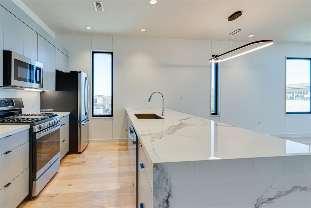 1023 Lipscomb Street, Unit 302 Fort Worth, TX 76104 - Photo 7 of 30 a kitchen that has a refrigerator a sink and a stove