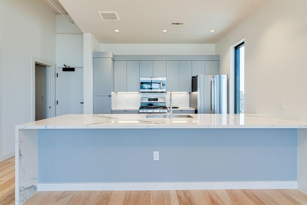 1023 Lipscomb Street, Unit 302 Fort Worth, TX 76104 - Photo 9 of 30 a view of kitchen with kitchen island a sink stainless steel appliances and cabinets
