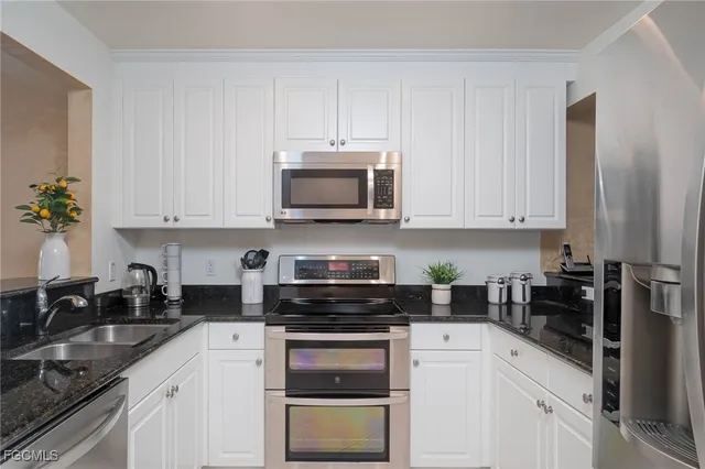 a kitchen with white cabinets and black appliances