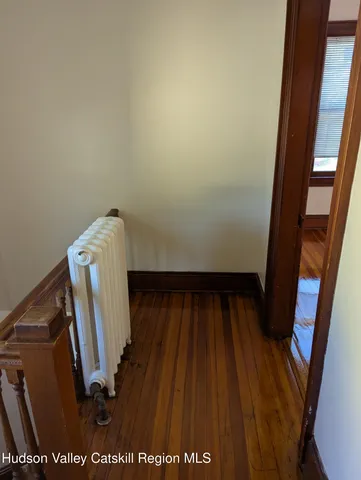 a view of an empty room with window and wooden floor