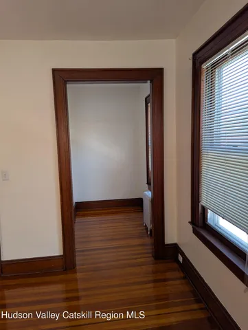 a view of an empty room with window and wooden floor