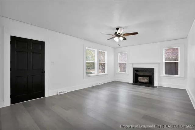 an empty room with windows fireplace and a fireplace