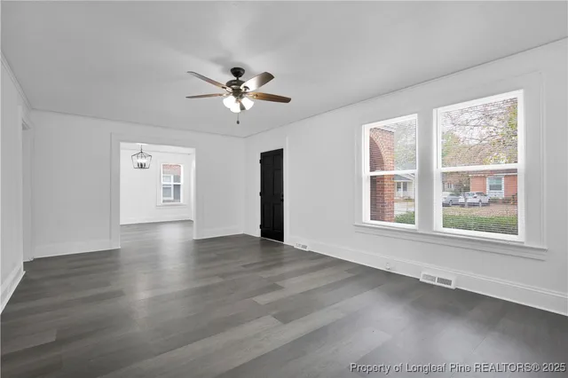 a view of an empty room with a window and wooden floor