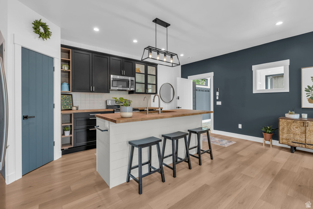 1766 West Tollgate Cyn Road Coalville, UT 84017 - Photo 31 of 59 Contemporary kitchen featuring black cabinetry, light wood-finish countertops, stainless steel appliances, and a central island with bar seating
