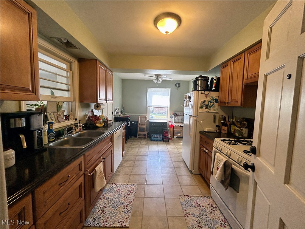 13678 Cedar Road Cleveland, OH 44118 - Photo 3 of 24 Kitchen (lower unit) featuring light tile patterned floors, white appliances, brown cabinetry, a sink, and dark countertops