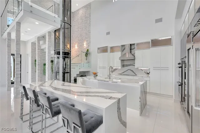 a kitchen with stainless steel appliances kitchen island granite countertop a dining table chairs and a refrigerator