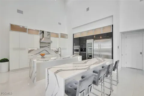 a kitchen with stainless steel appliances a white table chairs and a refrigerator