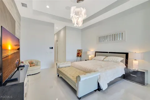 a bedroom with a bed and a flat tv screen on dresser