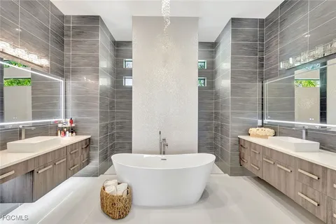 a bathroom with a tub double vanity sink and mirror