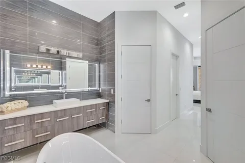 a spacious bathroom with a double vanity sink a mirror and a bathtub