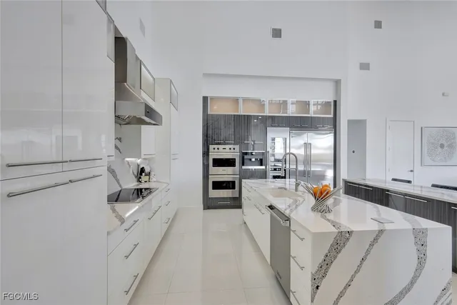 a large white kitchen with cabinets a sink and stainless steel appliances