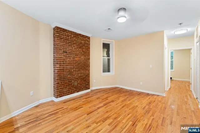 a view of an empty room with wooden floor and a bathroom