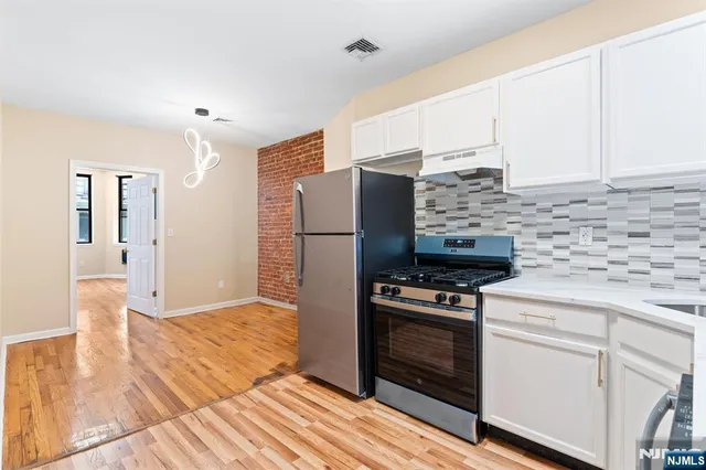 a kitchen with kitchen island wooden floors appliances and cabinets