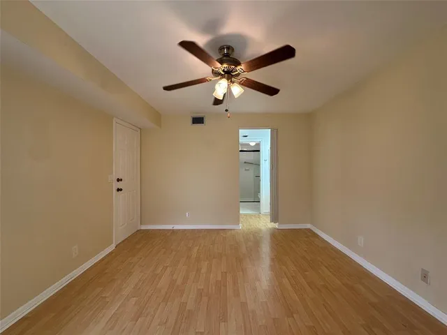 a view of a room with wooden floor and a ceiling fan