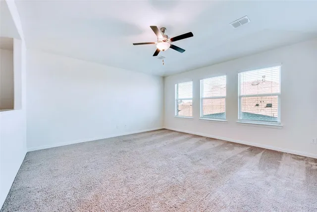 an empty room with windows and ceiling fan