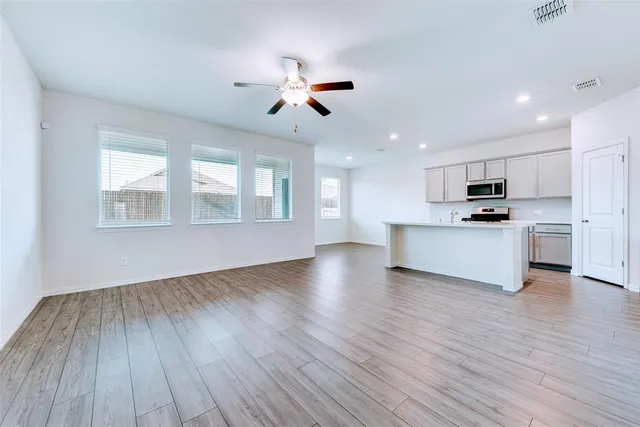 a view of a kitchen with wooden floor a sink a refrigerator and window