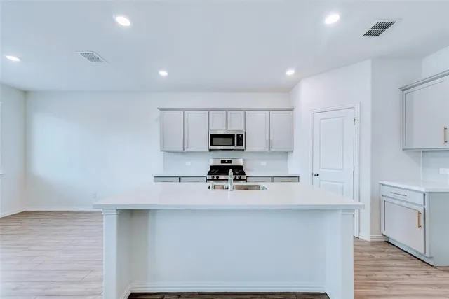 a kitchen with stainless steel appliances a refrigerator a stove and white cabinets