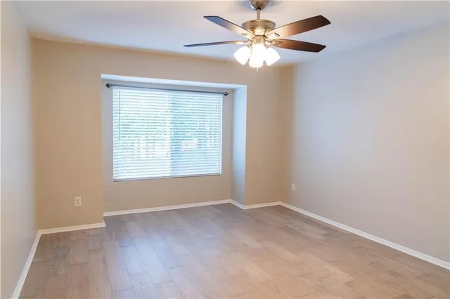 an empty room with a window and a fan