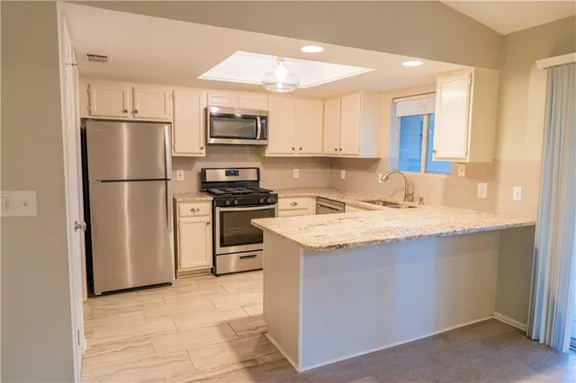 a kitchen with kitchen island a refrigerator sink and cabinets
