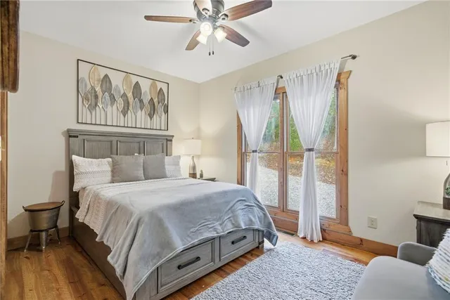 a bedroom with a bed painting on wall and a large window