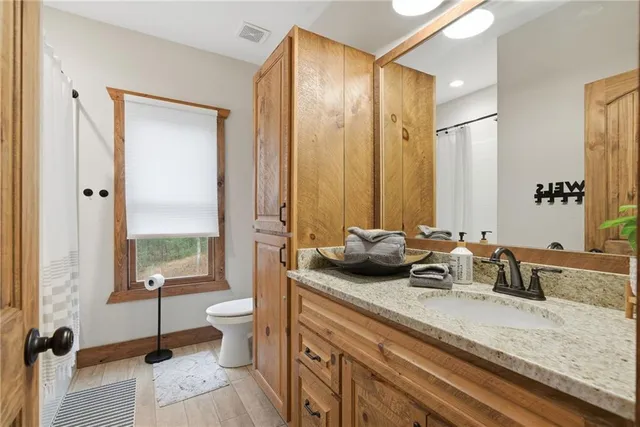 a bathroom with a granite countertop sink a toilet and a large mirror