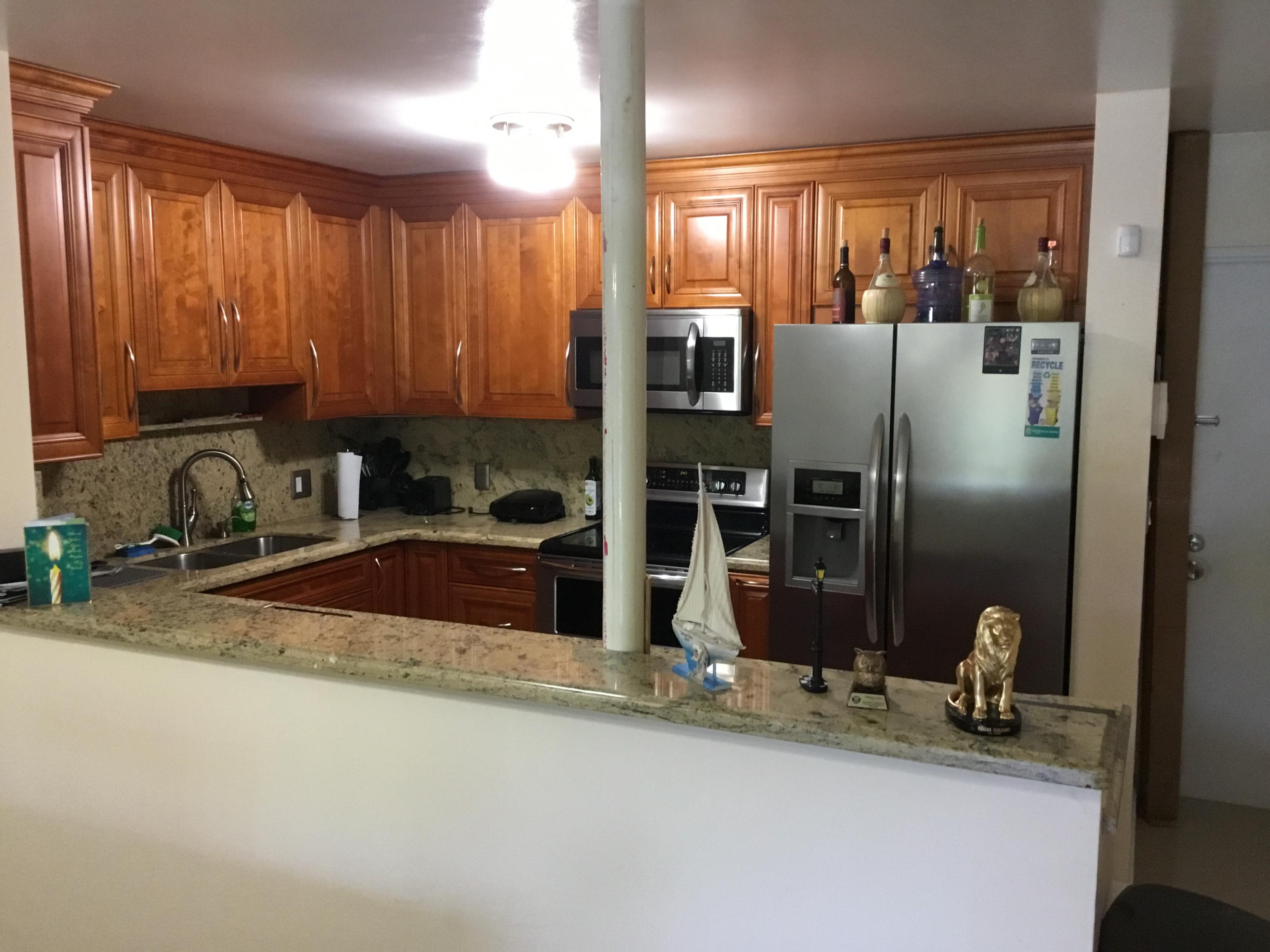 906 Southwest 9th St Circle, Unit 106 Boca Raton, FL 33486 - Photo 3 of 26 a kitchen with stainless steel appliances granite countertop a sink refrigerator and cabinets