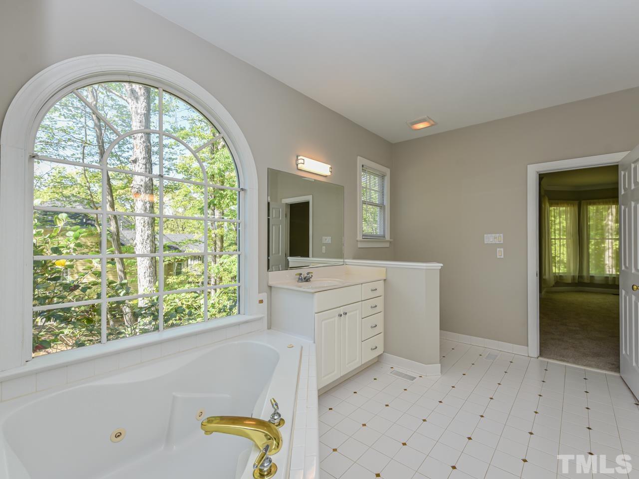 5820 Orchid Valley Road Raleigh, NC 27613 - Photo 20 of 31 a bathroom with a granite countertop sink a large mirror and a bathtub next to a window