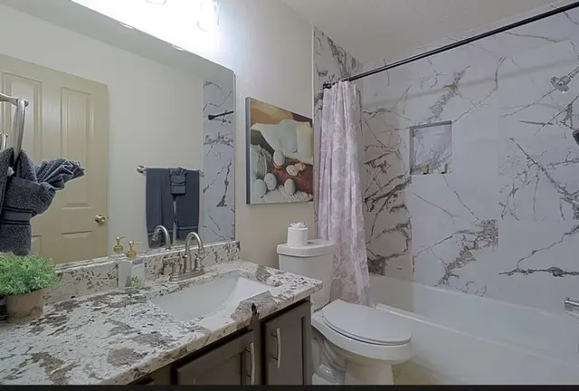 a bathroom with a granite countertop sink toilet and shower
