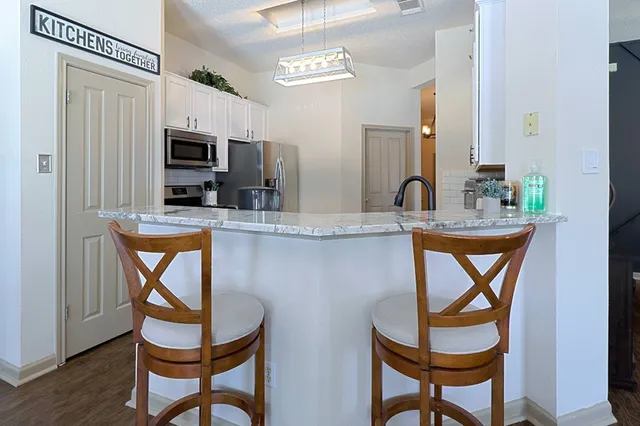 a kitchen with stainless steel appliances granite countertop a dining table and chairs