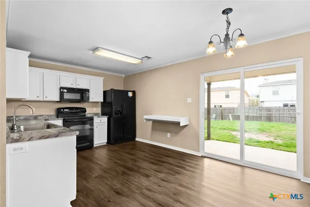 a kitchen with a refrigerator a stove top oven a sink and dishwasher with wooden floor