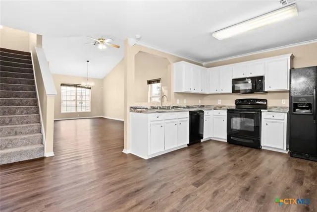 a kitchen with stainless steel appliances granite countertop a stove top oven a sink dishwasher and a refrigerator with wooden floor