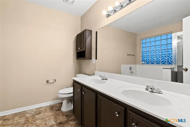 a bathroom with a granite countertop sink toilet and mirror