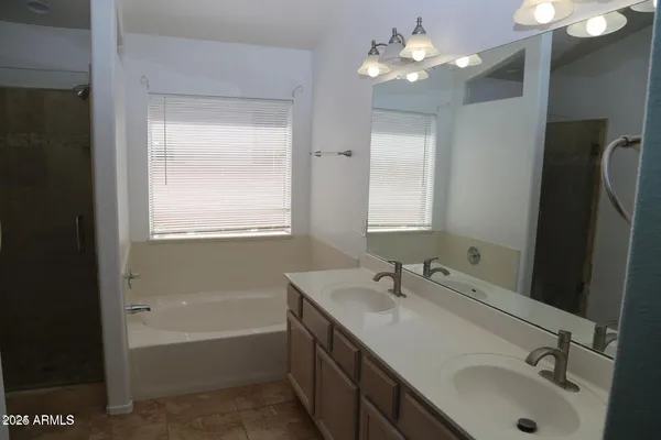 a bathroom with a tub sink double vanity and shower