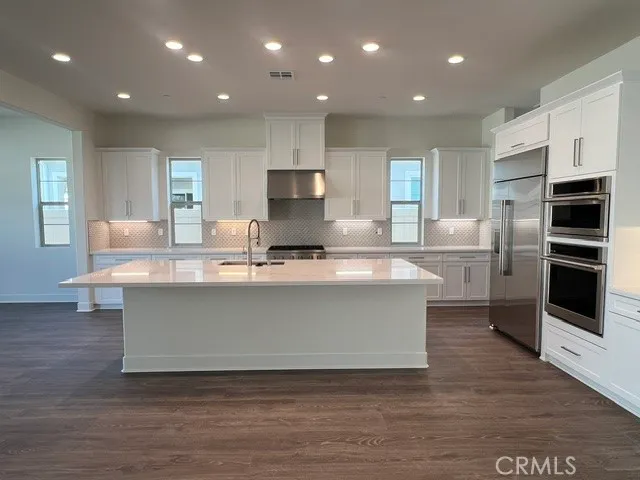 a large kitchen with stainless steel appliances a large counter top a stove a sink and a refrigerator