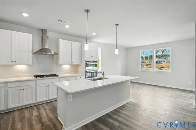 a large kitchen with stainless steel appliances granite countertop a stove a sink a center island a stove and a wooden floor