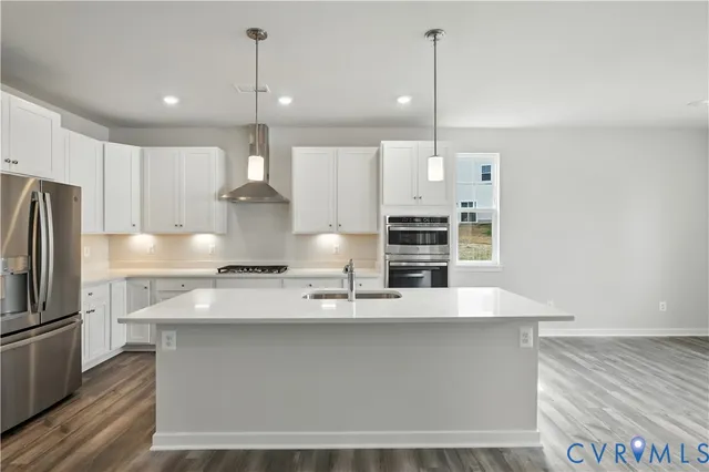 a large kitchen with stainless steel appliances a large counter top a stove and a refrigerator