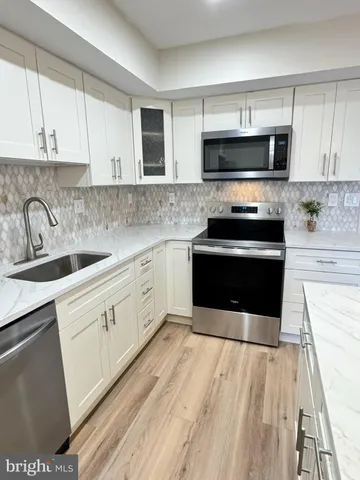 a kitchen with stainless steel appliances white cabinets and a refrigerator