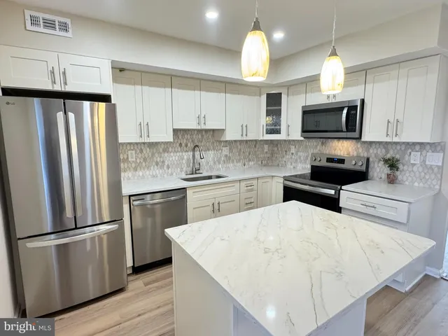 a kitchen with stainless steel appliances white cabinets a sink a stove a refrigerator and cabinets