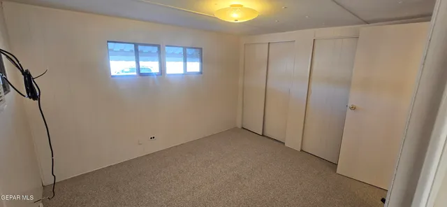 a view of an empty room with window and closet area