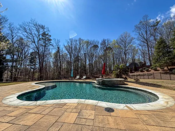 a view of swimming pool with lawn chairs and plants