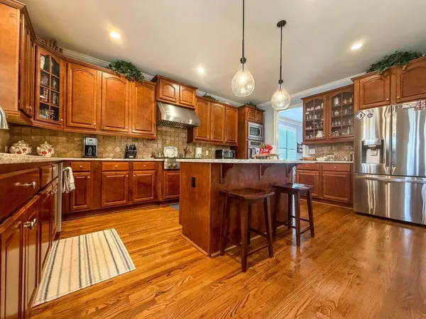 a kitchen with stainless steel appliances a dining table chairs sink and wooden floor