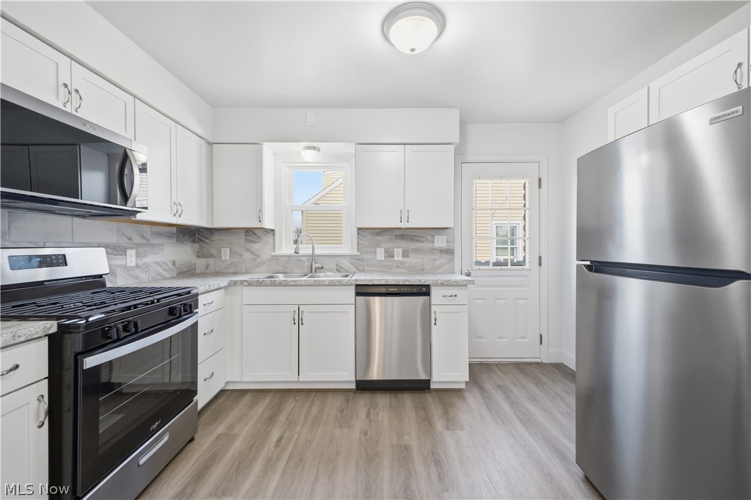 227 Wilson Street Struthers, OH 44471 - Photo 11 of 44 Kitchen with stainless steel appliances, white cabinets, light wood finished floors, decorative backsplash, and light stone countertops