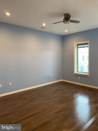 an empty room with wooden floor fan and windows