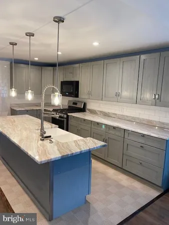 a kitchen with kitchen island granite countertop a sink a counter top space appliances and cabinets