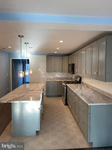 a kitchen with stainless steel appliances granite countertop a sink a stove and a refrigerator