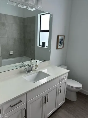 a bathroom with a granite countertop toilet sink and mirror