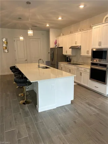 a kitchen with stainless steel appliances a stove a sink a refrigerator a center island and chairs