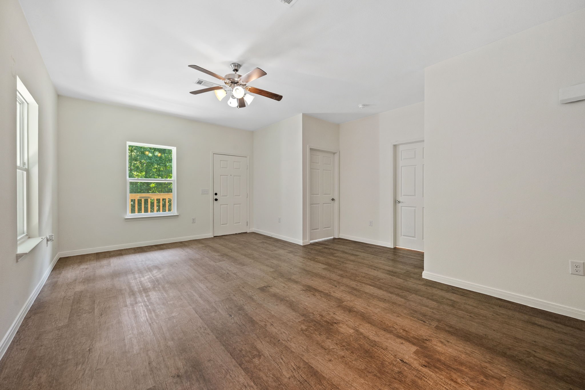 325 Cemetery Road Coldspring, TX 77331 - Photo 4 of 31 an empty room with wooden floor chandelier fan and windows