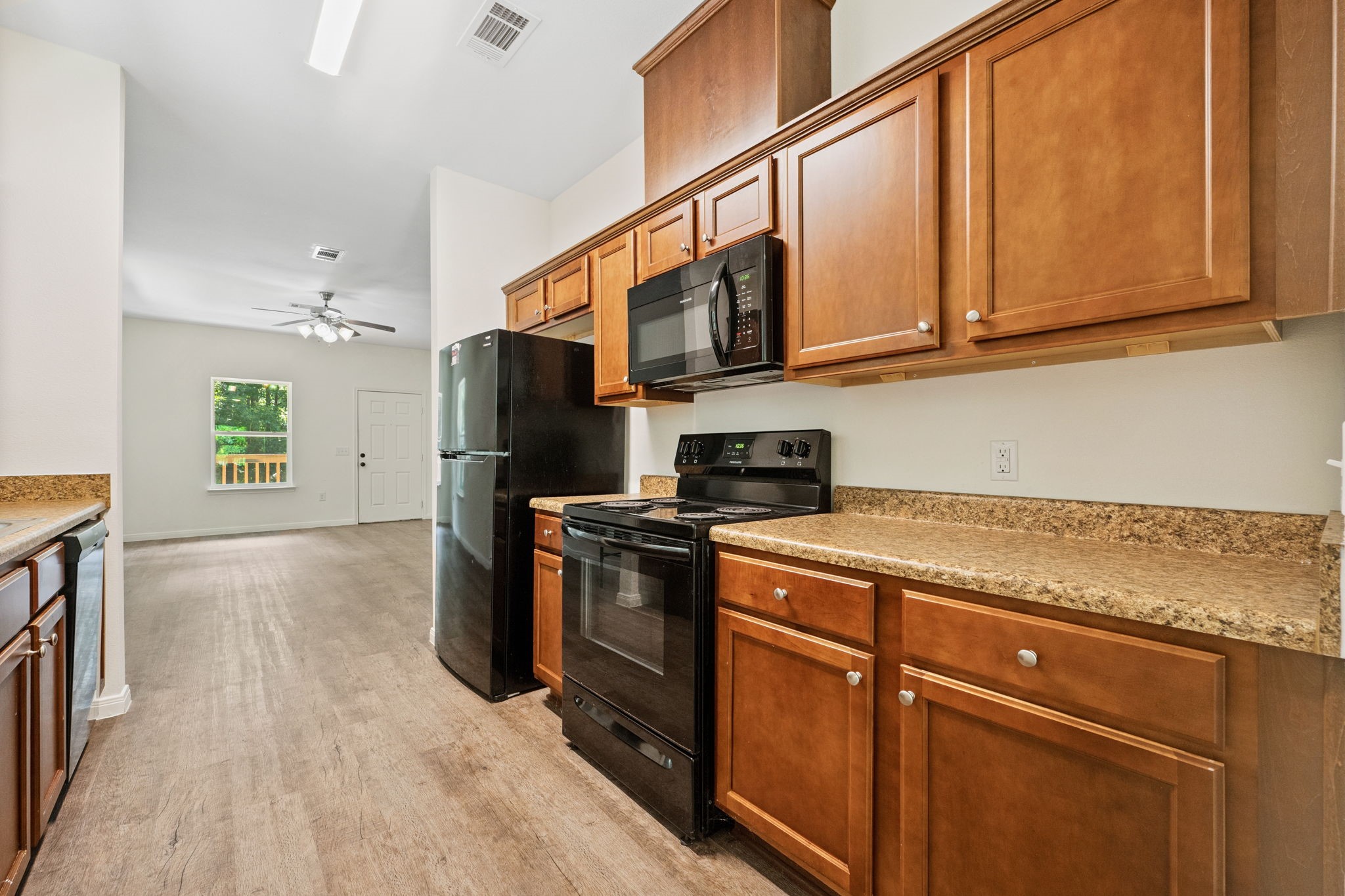 325 Cemetery Road Coldspring, TX 77331 - Photo 7 of 31 a kitchen with stainless steel appliances granite countertop a refrigerator a stove and a sink with wooden floor